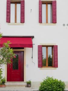 a red door on a white building with windows at Casa Agostini Bed and Breakfast in Farra di Soligo
