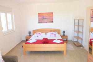 a bedroom with a bed with red sheets and pink pillows at Villa Luger 1. Stock in Ražanj +42 photos