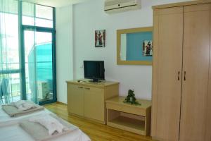 a bedroom with a bed and a television on a cabinet at Del Sol Private Apartments in Bŭnzareto