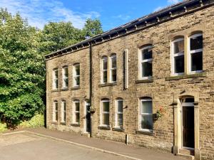 Un edificio de ladrillo con ventanas a los lados. en The Old Riverside School House Apt 5, en Hebden Bridge