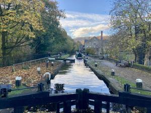 a canal with a boat in the middle of it at The Old Riverside School House Apartment 5 in Hebden Bridge