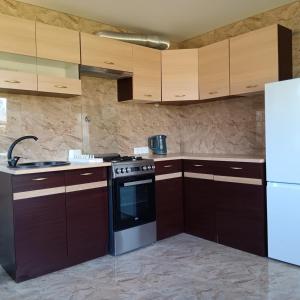 a kitchen with wooden cabinets and a stove and a refrigerator at Valva vila in Luokesos Sen