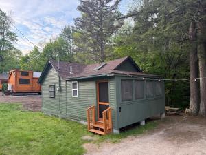a green tiny house sitting in a yard at EverHaus Cabin by the Brook - Harvard Brook Cabins in Lincoln