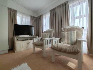 a living room with two chairs and a flat screen tv at The River House - Main House in Colchester