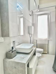 a white bathroom with a sink and a toilet at Appartamento Debbis Home Misano Adriatico in Misano Adriatico