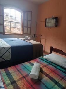 a bedroom with two beds and a tv on the wall at Hostel do Mirante in Ouro Preto