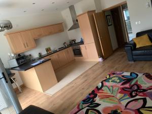 a kitchen with wooden cabinets and a living room at Pennisula Apartment in Portrush