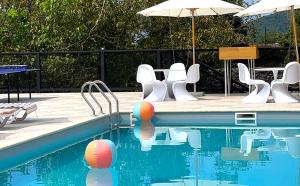 a swimming pool with white chairs and an umbrella at Hotel Chateau Kvareli in Kvareli