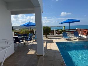 ein Haus mit Swimmingpool und Stühlen und Sonnenschirmen in der Unterkunft Villa Aqua Sunrise 1km From Beach With Sea Views in Coral Bay