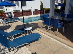 einen Pool mit blauen Stühlen, einem Tisch und einem Sonnenschirm in der Unterkunft Villa Aqua Sunrise 1km From Beach With Sea Views in Coral Bay