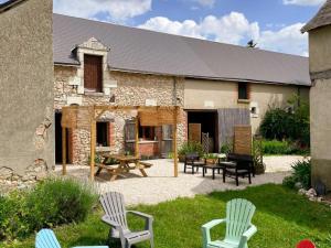 a patio with chairs and a table and a building at Gîte à Oisly près des Châteaux de la Loire avec Parking et Animaux Bienvenus - FR-1-491-469 in Oisly