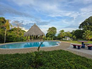 a swimming pool with a picnic table and a hut at Finca Hotel Galilea Doradal in Doradal