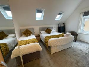 a bedroom with two beds and two windows at Kantara Guest House in Bournemouth