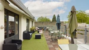 a patio with tables and chairs and umbrellas at Campanile NATURE - Marne La Vallee Chelles - Villepinte in Chelles