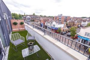 a balcony with two chairs and a street with houses at Brand-New Top-Floor Flat with Stunning Balcony & Parking in Borehamwood