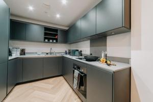 a kitchen with gray cabinets and a wooden floor at Luxury Two Bedroom Birmingham City Centre Apartment in Birmingham