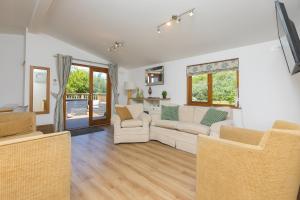 a living room with a white couch and chairs at Costentyn, Tor Down Quarry in Bodmin