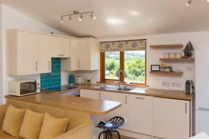 a kitchen with white cabinets and a sink and a window at Costentyn, Tor Down Quarry in Bodmin