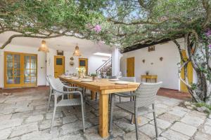 San PriamoにあるVilla La Scuderia I Unique Beachfront Villaのダイニングルーム(木の下にテーブルと椅子付)