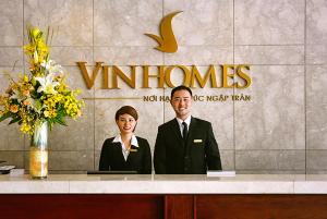 two people sitting at a counter in front of a sign at Vinhomes Time City Luxury Apartment in Ha Noi in Hanoi