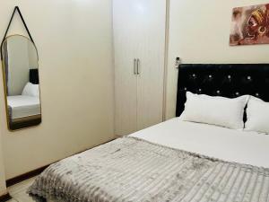 a bedroom with a large bed and a mirror at Brilliant Home in Gaborone