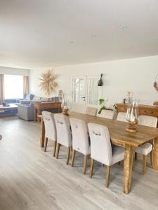 Un comedor con una mesa de madera y sillas blancas. en MaïTyNa - Tomorrowland Stay, en Rumst