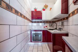 a red and white kitchen with red cabinets at GuestHost - Villa Vittoria - Casa sullo Scoglio in Mazzeo +7 photos
