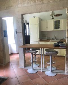 Una cocina con una mesa de madera y taburetes. en La maison de Léandre - Medoc, en Saint-Seurin-de-Cadourne