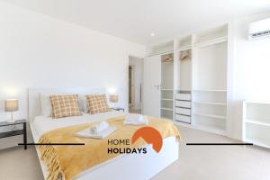 a white bedroom with a bed with a home holidays sign on it at #171 Páteo 2 Flat by Home Holidays in Albufeira +50 photos