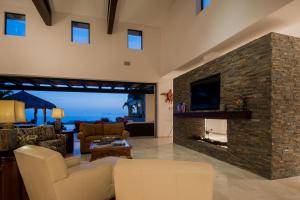 a living room with a stone fireplace with a tv at Villa de Suenos by Cabo Villas in San José del Cabo