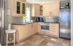 a kitchen with wooden cabinets and a stainless steel refrigerator at 3 Bedroom Awesome Home In Gursken in Larsnes