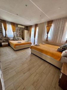 two beds in a large room with windows at Apartments Tadic in Petrovac na Moru
