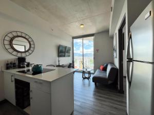 a kitchen with a refrigerator and a living room at Lux at 15, Pool, Gym and Stylish City Stay in Hatillo
