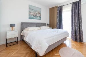 a bedroom with a large white bed and a window at Seaside Apartments Slavica in Petrcane
