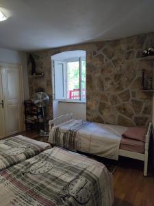 two beds in a room with a stone wall at Authentic stone house by the sea in Milna +48 photos