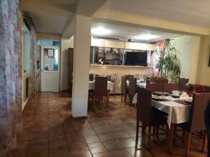 a dining room with tables and chairs and a kitchen at Pensiune Casa Barcaru in Azuga