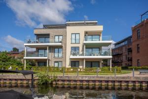 Nordlicht - Modernes Apartment auf Seegrundstück في مالتشو: مبنى بجانب تجمع المياه