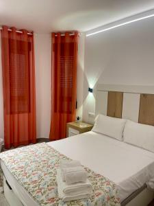 a bedroom with a large bed with red curtains at Apartamentos Palma del Río CAROLA in Linares