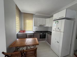 a kitchen with a wooden table and a white refrigerator at Cadde üzeri in Özdere
