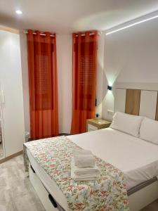 a bedroom with a white bed with red curtains at Apartamentos Palma del Río CAROLA in Linares