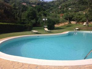 a large swimming pool in a yard with two chairs at Appartamento La collina del sole in Lerici