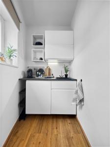 a kitchen with white cabinets and a wooden floor at Exklusives Studio 4 in Steinfeld in Steinfeld