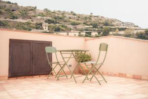 two chairs and a table on a balcony with a door at Spighe e Fenicotteri in Modica
