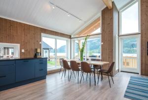 a kitchen with a table and chairs and windows at Pluscamp Mageli in Bjørge