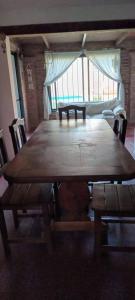 un grande tavolo in legno con sedie e una grande finestra di Villa Paz a Villa Allende