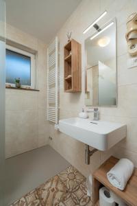 un bagno con un lavandino bianco e uno specchio di Rooms & Apartments Pr Matjon a Bled Altre 37 foto