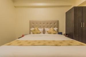 a bedroom with a large white bed with yellow pillows at Super Hotel O Palace Inn Near Don Bosco (Borivali) Metro Station in Mumbai