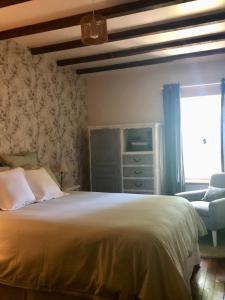 a bedroom with a bed and a chair and a window at Le Cerisier Saint-Barbant in Saint-Barbant