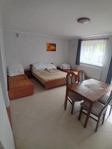 a room with two beds and a table and a dining room at Domimat-Lila in Dębki
