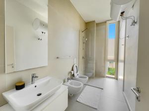 een witte badkamer met 2 toiletten en een wastafel bij Mèla Twin Villa Green Coast in Himare +11 foto's